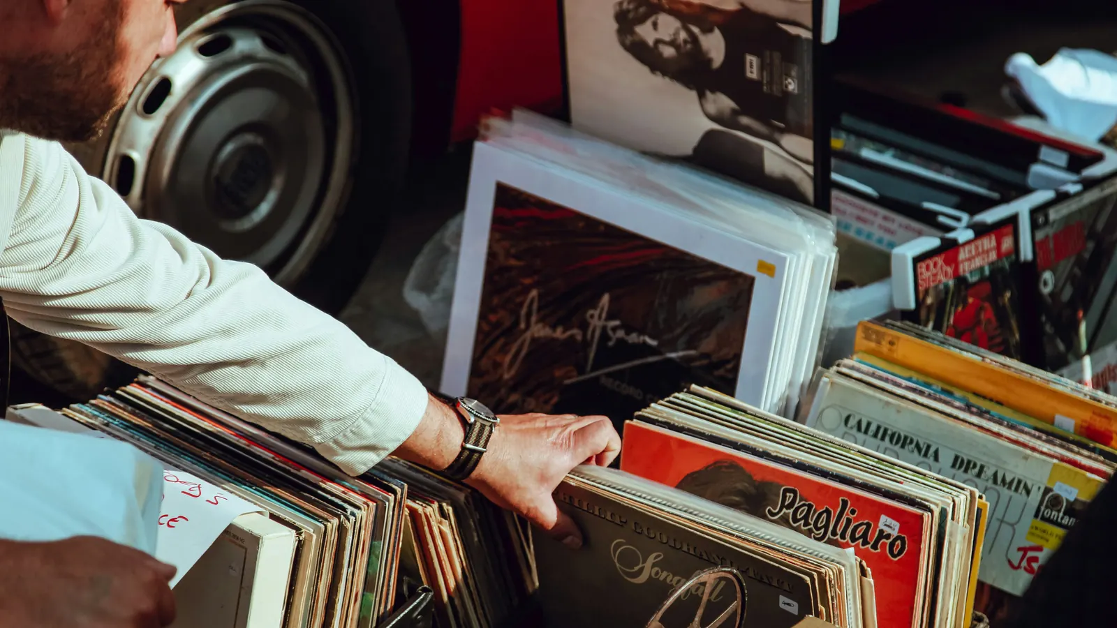 Someone flipping through a crate of vinyl records at a flea market