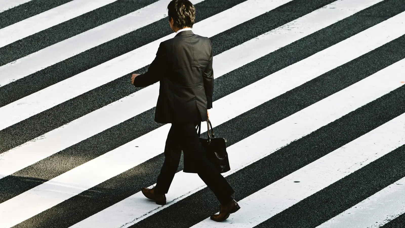 A businessman in a suit walking across a pedestrian crossing