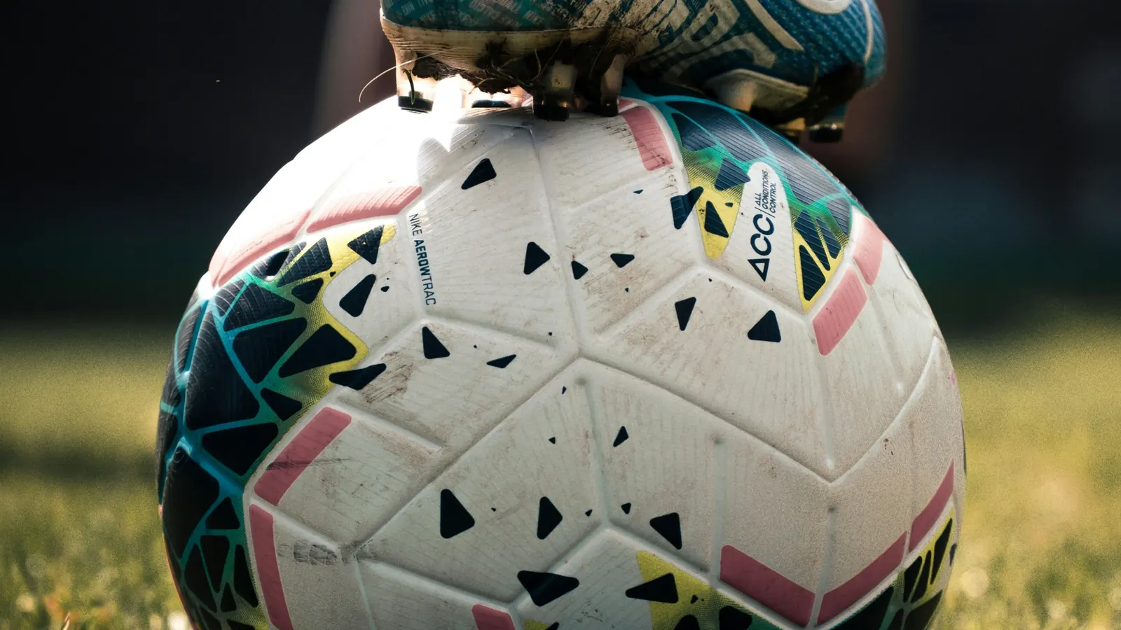 A football on a grass pitch in evening light