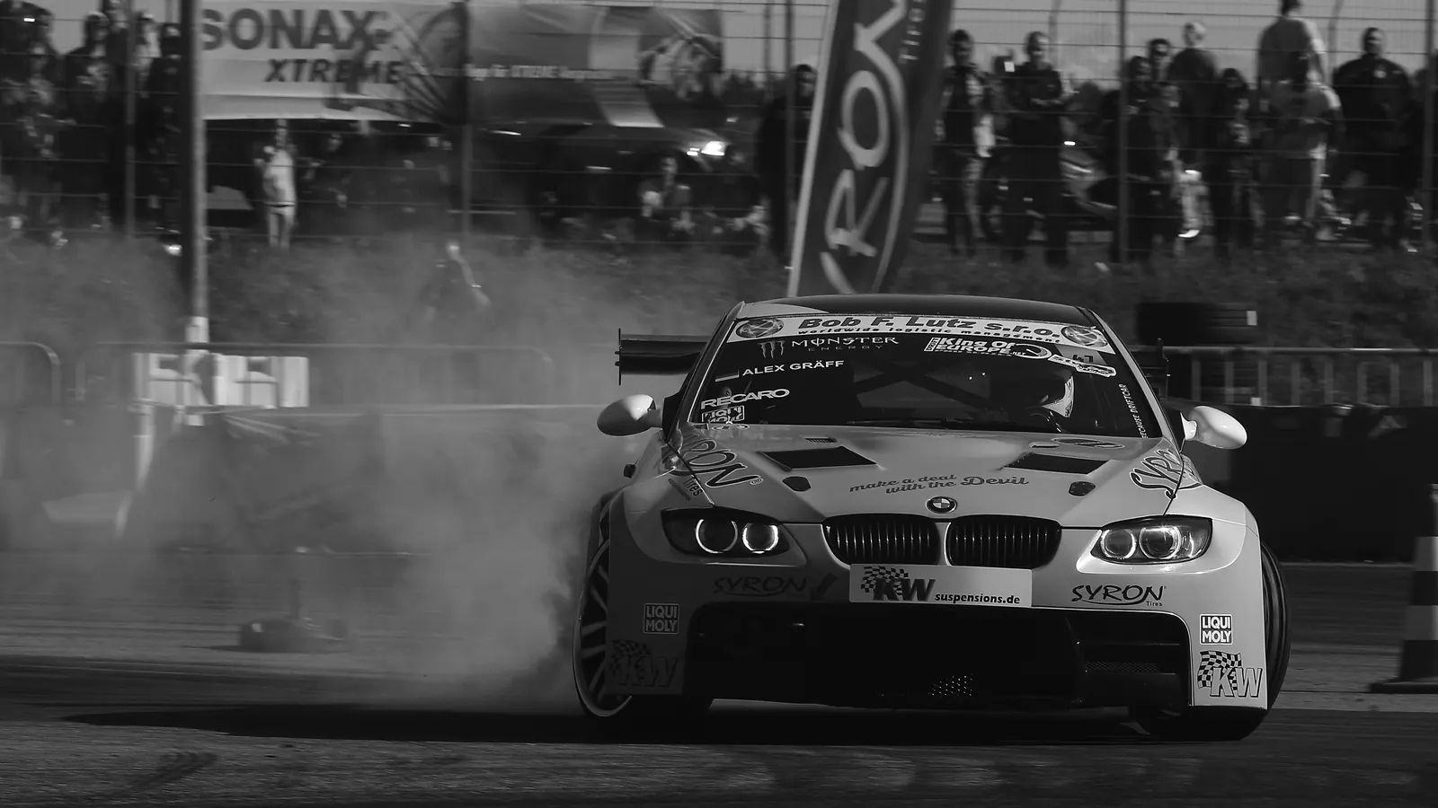 A black-and-white photo of a car drifting through a cloud of tyre smoke